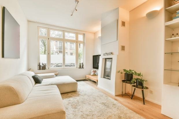 Bright living room with a pale corner sofa, rug and window after a domestic clean