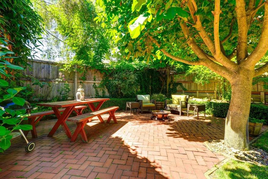 Brick patio with garden furniture under a tree after jetwashing